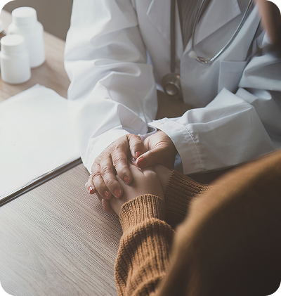 A clinician holding a patient’s hands during a consultation.